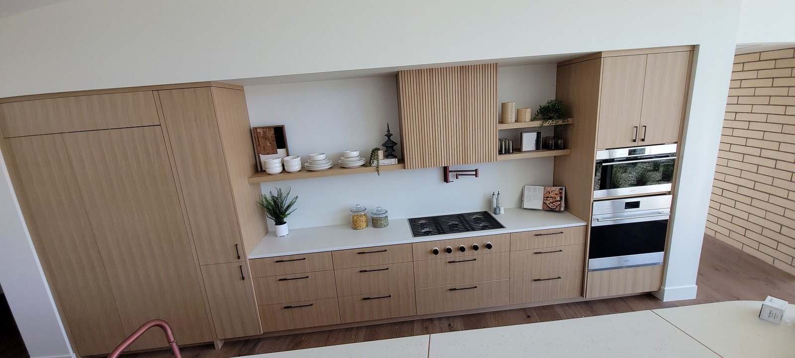 Contemporary kitchen built-in cabinetry with light wood grain and integrated appliances