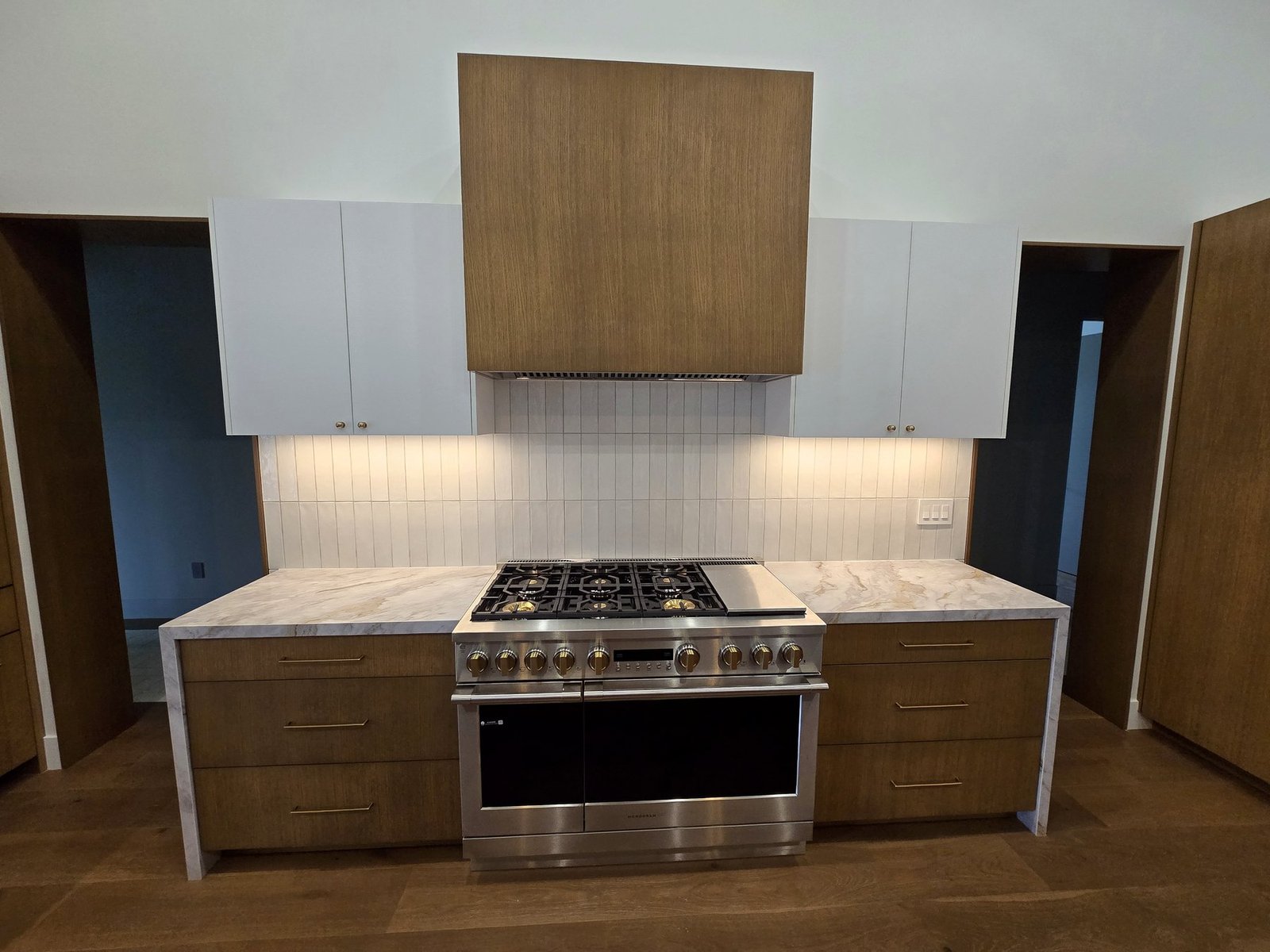 Custom kitchen range wall cabinet installation with white and walnut cabinetry